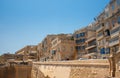 Detail shot of the coast of Malta with historic houses behind the thick wall. The typical traditional balconies can be seen on the