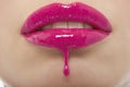 Detail shot of pink lipgloss dripping from woman's lips