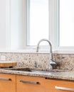 A kitchen sink detail with wood cabinets and granite countertop. Royalty Free Stock Photo