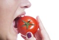 Detail shot of young woman eating tomato over white background