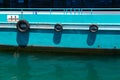 Detail of the side of a rusty old ferry boat of turquoise color with water reflection.