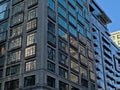 Detail of a skyscraper with reflectio n of other buildings and blue sky in the windows