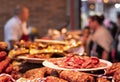 Detail of some typical and delicious dried spanish sausages in a butcher shop with butcher and customer in a blurred background