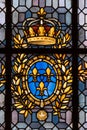 Detail of stained glass panel with a crown, gold leaves, three gold fleur de lys on blue background in St. Denis