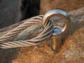 Detail of steel bolt anchor eye in rock. The end knot of steel rope. Climbers path in rocks via ferrata. Iron twisted rope fixed Royalty Free Stock Photo