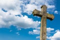 Old gothic Christian stone cross on dramatic blue sky background with white clouds Royalty Free Stock Photo