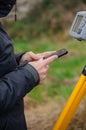 detail of a surveyor's hands configuring the total station with the mobile phone, topography works