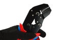 Detail of terminal crimping press pliers with closed jaws, held in left hand in thin black nylon/polyester/spandex glove