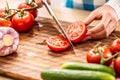 Detail of a tomato freshly cut into halves on a cutting board with cucumber, garlic and more tomatoes aside