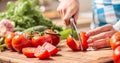 Detail of a tomato freshly cut into halves on a cutting board with cucumber, garlic and more tomatoes aside