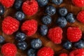 Detail top view on mixed blueberries and raspberries on wooden p