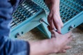 Detail of a turquoise metal staircase that is assembled by a worker with a screwdriver