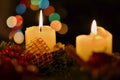 Detail of two burning candles with background made of colorful bokeh lights placed on the Christmas tree