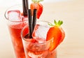 Detail of two glasses of strawberry cocktail with ice on light wood table Royalty Free Stock Photo