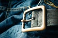 close up detail of an unbuckled leather belt on a faded pair of blue jeans Royalty Free Stock Photo