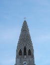 Detail of the upper part of the Hallgrimskirkja church where you can see the details of the antennas, the cross and tourists