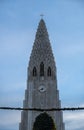 Detail of the upper part of the Hallgrimskirkja church where you can see the details of the antennas, the cross and tourists