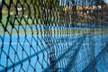 view of a blue synthetic tennis court through the central net