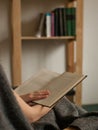 Detail view on book in hands with bookcase in background
