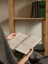 Detail view on book in hands with bookcase in background Royalty Free Stock Photo