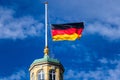 Detail view on German Flag at Halfmast, auf Halbmast, on the tower roof of Castle Karlsruhe, blue sky in background. Germany Royalty Free Stock Photo