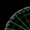 Detail view of an illuminated green and white ferris wheel and cabins in black night