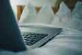 Detail view of a laptop keyboard sitting on a bed in hotel room. Vintage hotel room with laptop on the sheet. Concept of online Royalty Free Stock Photo