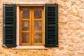 Wood window with open shutters and stone wall of mediterraean house