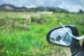 View of a rearview mirror of a car in a green grassy field Royalty Free Stock Photo