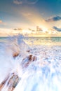 Detail view of rock on the beach, placed in the sand, with big water wave from the sea. Beautiful sunset above ocean with soft Royalty Free Stock Photo