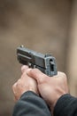 Shooter holding gun in hand and shooting. Close-up detail view
