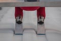 Detail view of a ski jumper on a large hill on snow prepared ski jump. Visible details of shoes or boots, skis and downward view