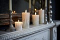 detail view of unlit white candles on a dust-free mantelpiece