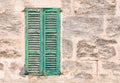 Ancient green wood window shutter with rustic old gray stone wall background Royalty Free Stock Photo