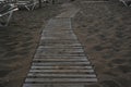 Detail view on wooden sidewalk or footpath in sandy beach in a holiday resort during sunrise. Royalty Free Stock Photo