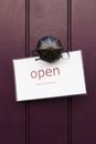 Detail of a vintage brass doorknob with open sign on a dark purple wooden door Royalty Free Stock Photo