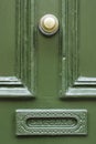 Detail of vintage green wooden door with brass doorknob knocker