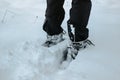 Detail of warm waterproof boots in deep fresh snow.Female feet in black shoes, winter walking in snow.Low angle view of standing