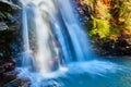 Detail of waterfall against cliff rocks with red sheets of rock and bright blue water Royalty Free Stock Photo