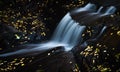 Small waterfall surrounded by golden leaves in autumn