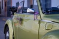 Detail of wedding ornament placed on the silver rearview mirror of a metallic green convertible car Royalty Free Stock Photo