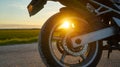 Detail of the wheel of a parked road motorcycle at sunset. Sun rays between the motorcycle wheel Royalty Free Stock Photo