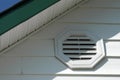 Detail of white aluminum siding, white vinyl vent, white soffit and dark green fascia