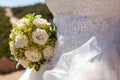 Detail of a white roses bouquet with bride`s dress