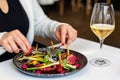 Detail of woman eating appetizing fresh mixed salad in fancy restaurant