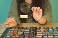 Detail of woman is hands with a magnifying glass and tweezers checking a stamp from her philately collection