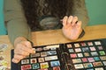 Detail of a woman is hands with a magnifying glass and tweezers checking a stamp from her philately collection