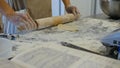 Detail of woman`s hand rolling out a dough with a rolling pin while making homemade pasta. Woman`s hands rolling dough Royalty Free Stock Photo