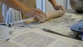 Detail of woman`s hand rolling out a dough with a rolling pin while making homemade pasta. Woman`s hands rolling dough Royalty Free Stock Photo