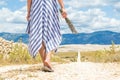 Detail of woman in summer dress holding bouquet of lavender flowers while walking outdoor through dry rocky